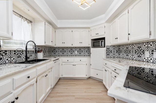 kitchen with dishwasher, sink, white cabinets, light stone counters, and light hardwood / wood-style floors