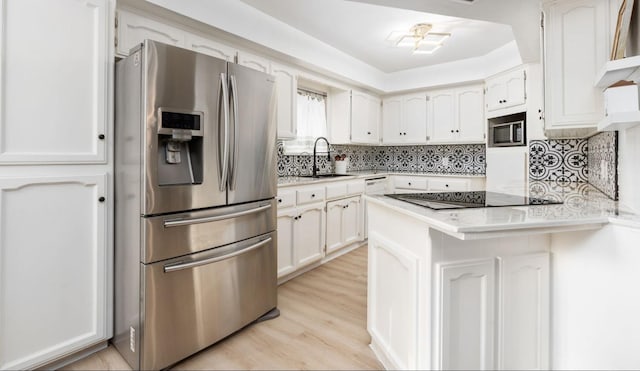 kitchen featuring sink, appliances with stainless steel finishes, kitchen peninsula, light hardwood / wood-style floors, and white cabinets