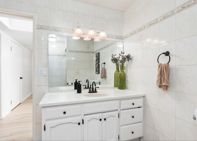 bathroom featuring vanity, wood-type flooring, and tile walls