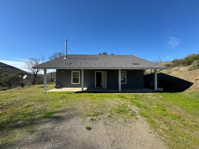 rear view of property with a yard, a shingled roof, and a patio