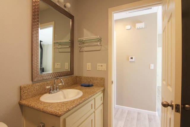 bathroom with baseboards, visible vents, wood finished floors, and vanity