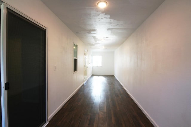 corridor with dark wood finished floors and baseboards