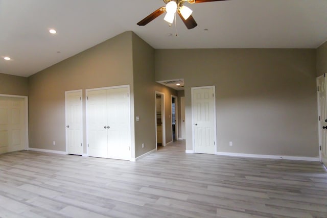 unfurnished bedroom featuring high vaulted ceiling, recessed lighting, baseboards, light wood-style floors, and two closets