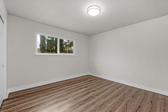 empty room featuring wood finished floors and baseboards