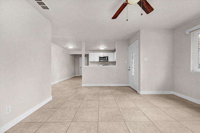 unfurnished living room featuring light tile patterned flooring, ceiling fan, visible vents, and baseboards