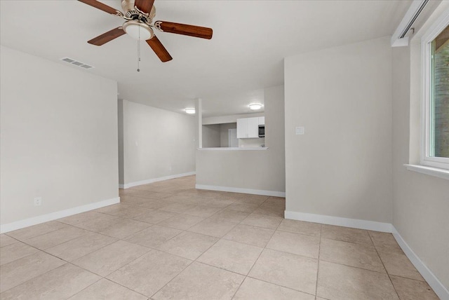 unfurnished room with light tile patterned floors, ceiling fan, visible vents, and baseboards