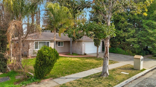 single story home with a garage, driveway, a front lawn, and stucco siding