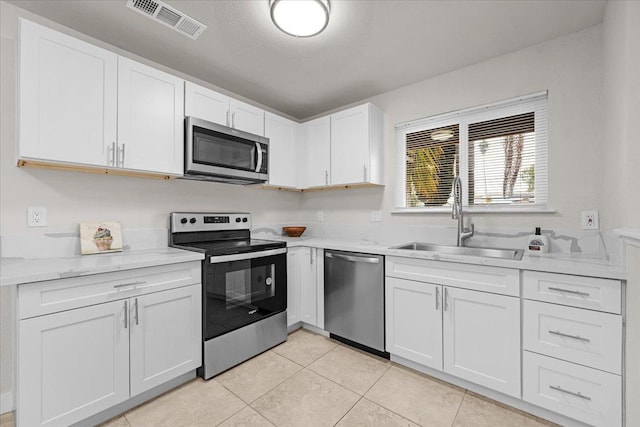 kitchen featuring light tile patterned floors, visible vents, white cabinets, appliances with stainless steel finishes, and a sink