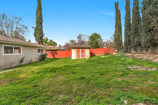 view of yard featuring a fenced backyard, a storage unit, and an outbuilding