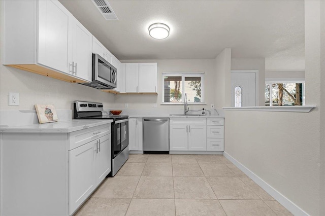 kitchen featuring light tile patterned floors, visible vents, white cabinets, appliances with stainless steel finishes, and a sink