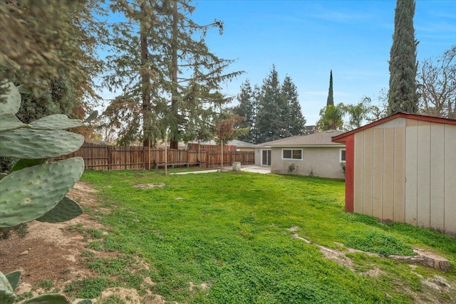 view of yard featuring an outbuilding, fence, and a storage unit