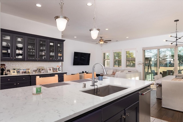 kitchen with pendant lighting, sink, ceiling fan, light stone counters, and light wood-type flooring