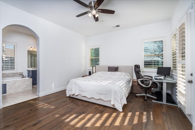 bedroom featuring ceiling fan, dark hardwood / wood-style flooring, and ensuite bath