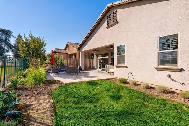 rear view of house with ceiling fan, a yard, and a patio