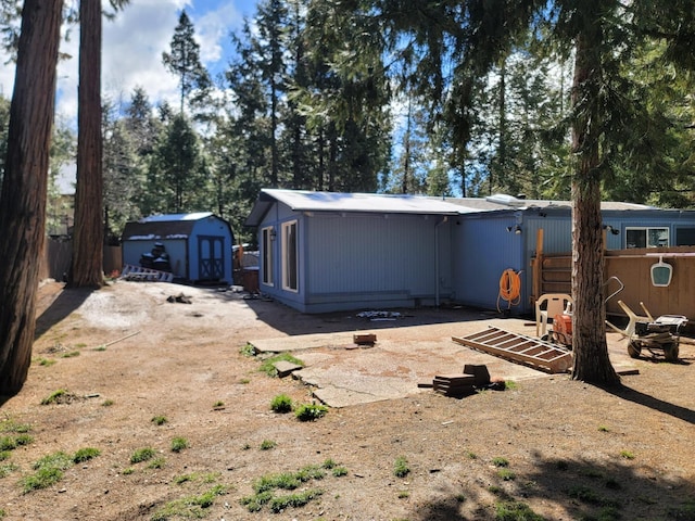 rear view of house with a storage shed, an outdoor structure, and fence