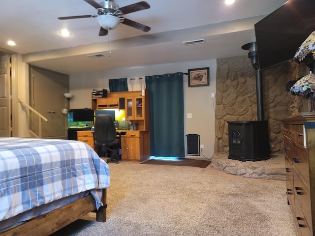 bedroom with a ceiling fan, visible vents, a wood stove, recessed lighting, and light colored carpet