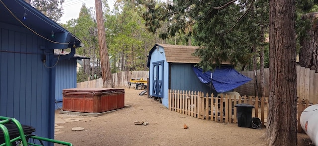 view of yard featuring an outbuilding, a hot tub, a storage shed, and fence