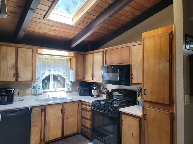 kitchen with a sink, vaulted ceiling with skylight, black appliances, and light countertops