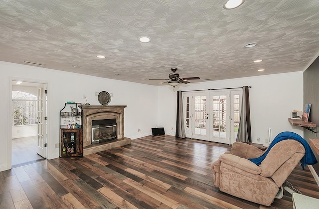 living room with dark wood-type flooring, plenty of natural light, french doors, and a textured ceiling