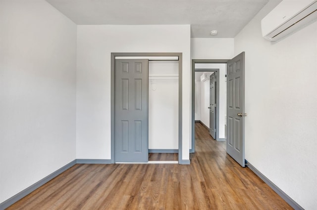 2567 S Rowell Ave, Fresno, CA 93725 - unfurnished bedroom with a wall mounted air conditioner, wood-type flooring, and a closet