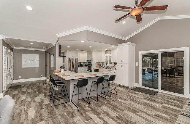 kitchen featuring stainless steel refrigerator, white cabinetry, lofted ceiling, a kitchen bar, and a large island