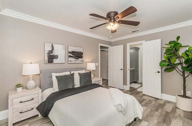 bedroom featuring ceiling fan, ornamental molding, ensuite bathroom, and hardwood / wood-style floors