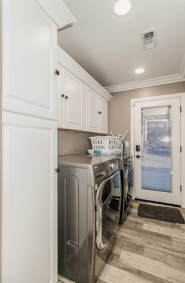 washroom featuring cabinets, washing machine and dryer, crown molding, and light hardwood / wood-style floors