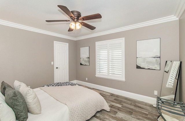 bedroom featuring ceiling fan, ornamental molding, and wood-type flooring