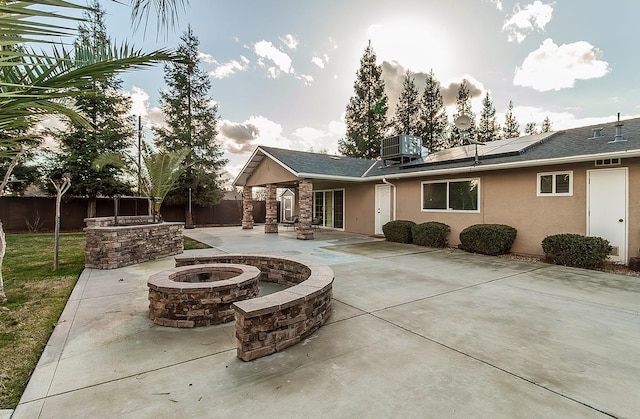 back of house with central AC, a patio, solar panels, and an outdoor fire pit