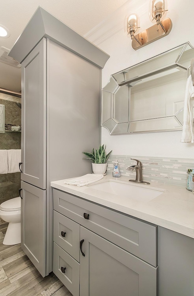 bathroom featuring vanity, hardwood / wood-style floors, backsplash, and toilet