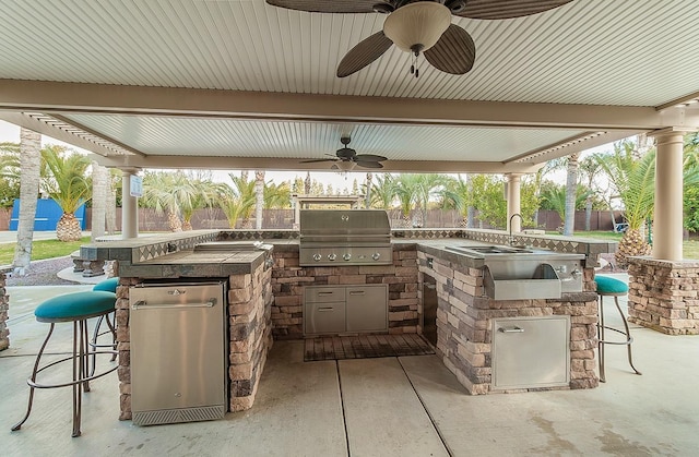 view of patio featuring exterior kitchen, area for grilling, ceiling fan, and a wet bar