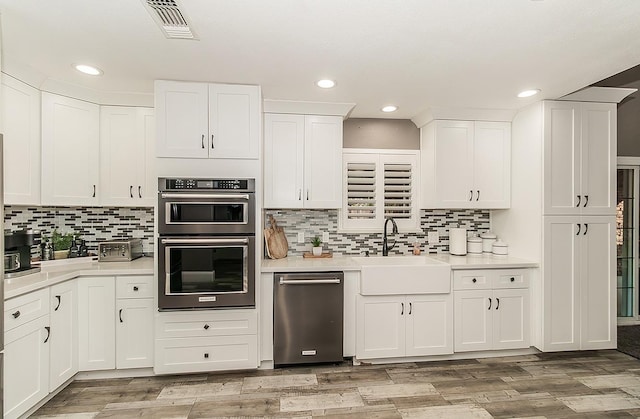 kitchen with sink, light hardwood / wood-style flooring, double oven, white cabinets, and backsplash