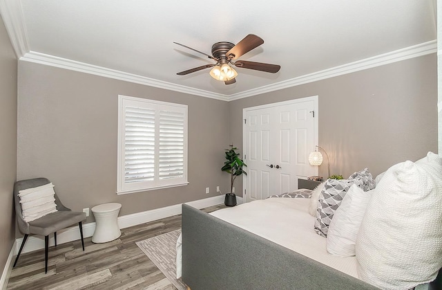 bedroom featuring ornamental molding, wood-type flooring, ceiling fan, and a closet