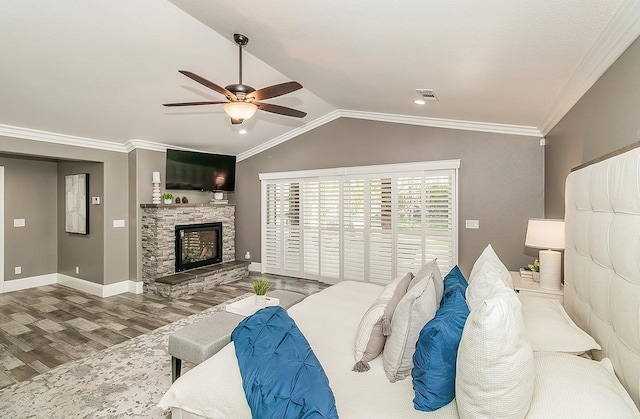 bedroom featuring a stone fireplace, lofted ceiling, hardwood / wood-style flooring, ceiling fan, and crown molding