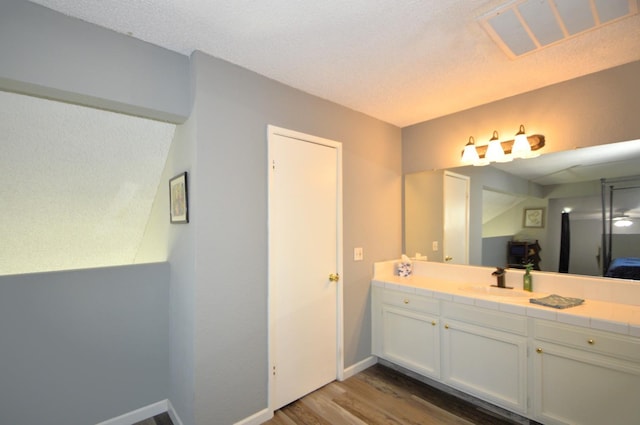 bathroom featuring hardwood / wood-style flooring, vanity, and a textured ceiling