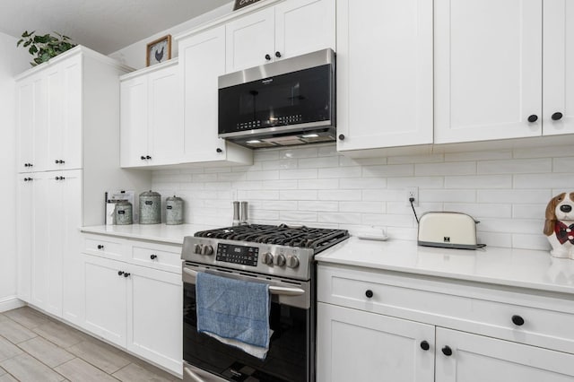 kitchen featuring white cabinetry, appliances with stainless steel finishes, backsplash, and light hardwood / wood-style flooring