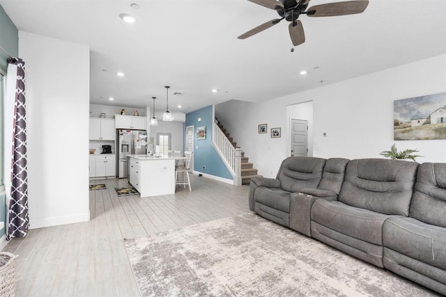 living room with ceiling fan, sink, and light hardwood / wood-style floors