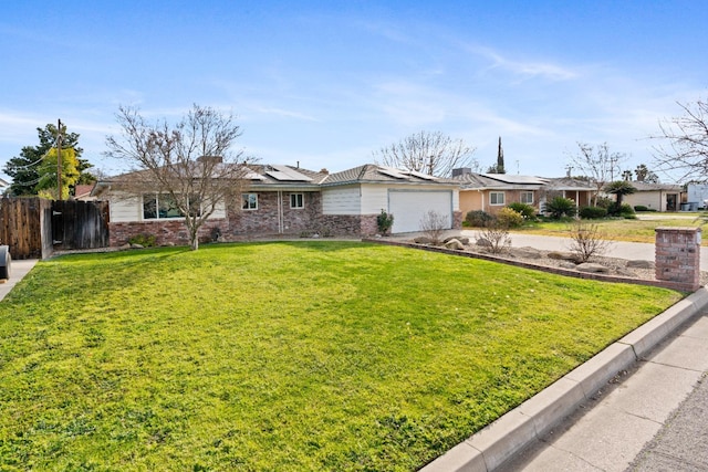 single story home featuring a garage, a front yard, and solar panels