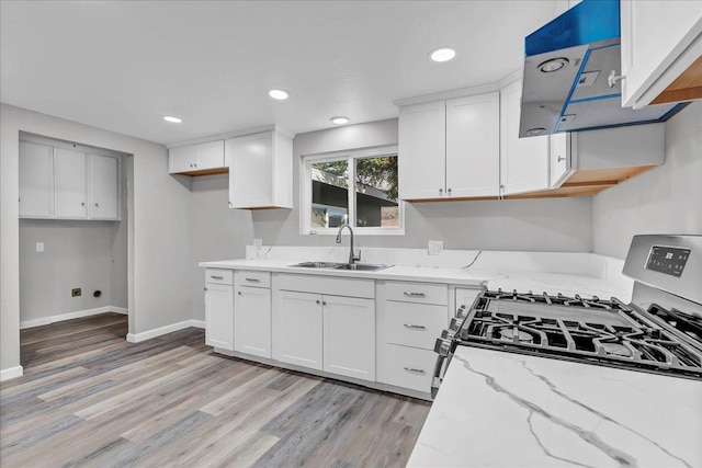 kitchen with white cabinetry, range hood, sink, and light stone counters