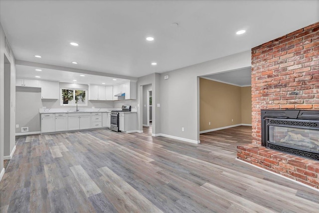 unfurnished living room with a brick fireplace, light hardwood / wood-style floors, and sink