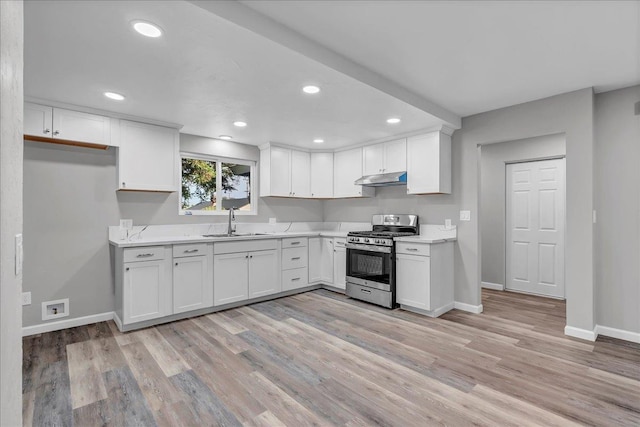 kitchen with gas range, sink, white cabinets, and light wood-type flooring