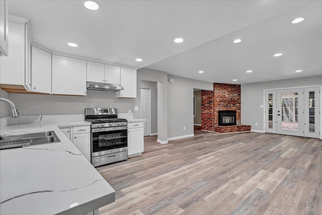 kitchen with white cabinetry, light stone countertops, sink, and stainless steel gas stove