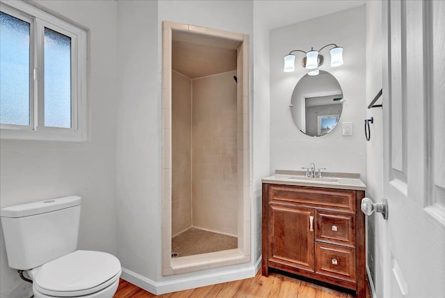 bathroom with vanity, tiled shower, hardwood / wood-style floors, and toilet