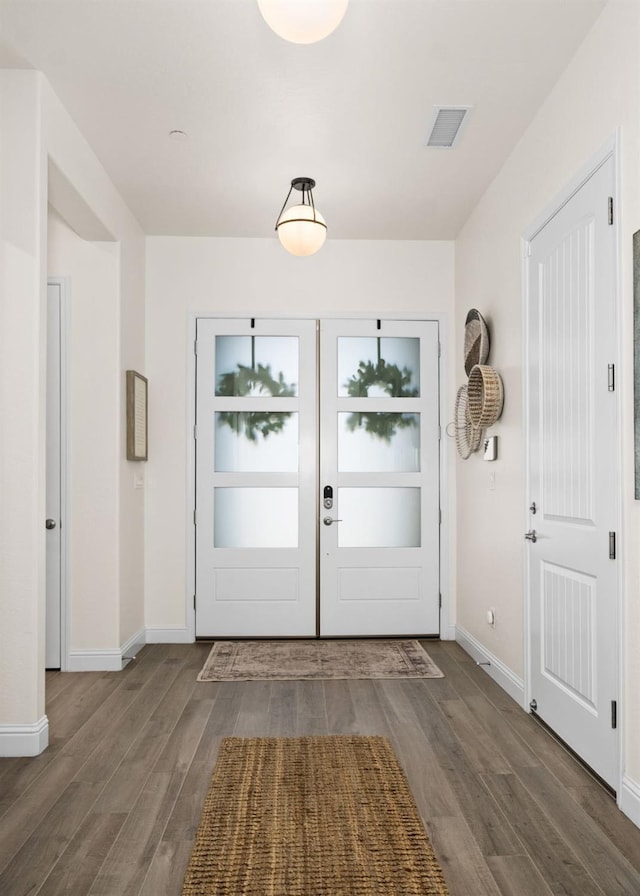 entryway with wood finished floors, visible vents, and baseboards