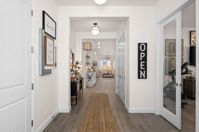 hallway with wood finished floors, baseboards, and french doors