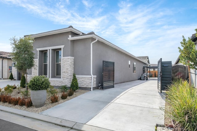view of property exterior featuring stone siding, fence, and stucco siding