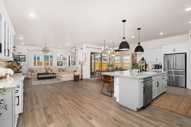 kitchen featuring light wood-type flooring, open floor plan, a notable chandelier, light countertops, and appliances with stainless steel finishes