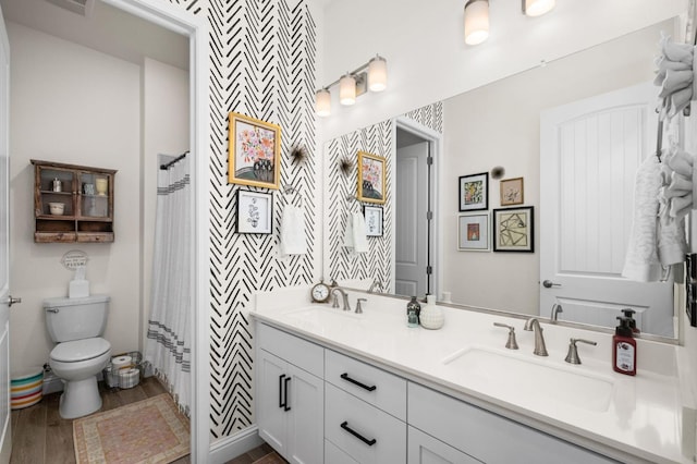 full bathroom with double vanity, toilet, wood finished floors, and a sink