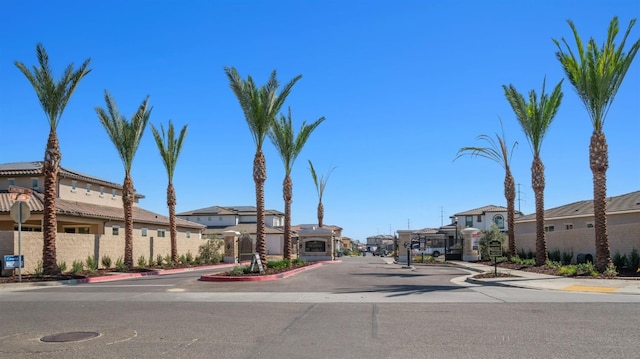 view of street featuring sidewalks, curbs, a gate, and a residential view