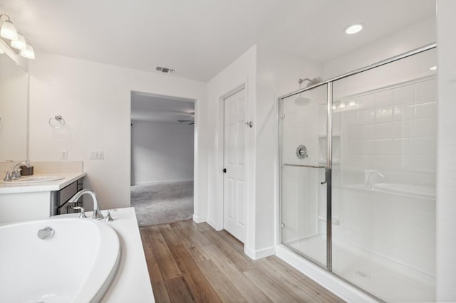 bathroom featuring plus walk in shower, wood-type flooring, and vanity